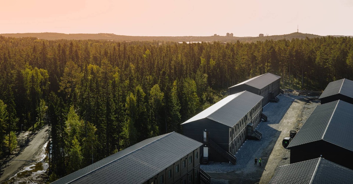 Drönarbild som visar flera tillfälliga boendehus i Luleå med skog och vacker himmel i bakgrunden